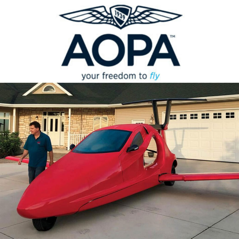 A Switchblade in a driveway facing the road with Sam Bousfield standing next to it, above is a logo of the AOPA