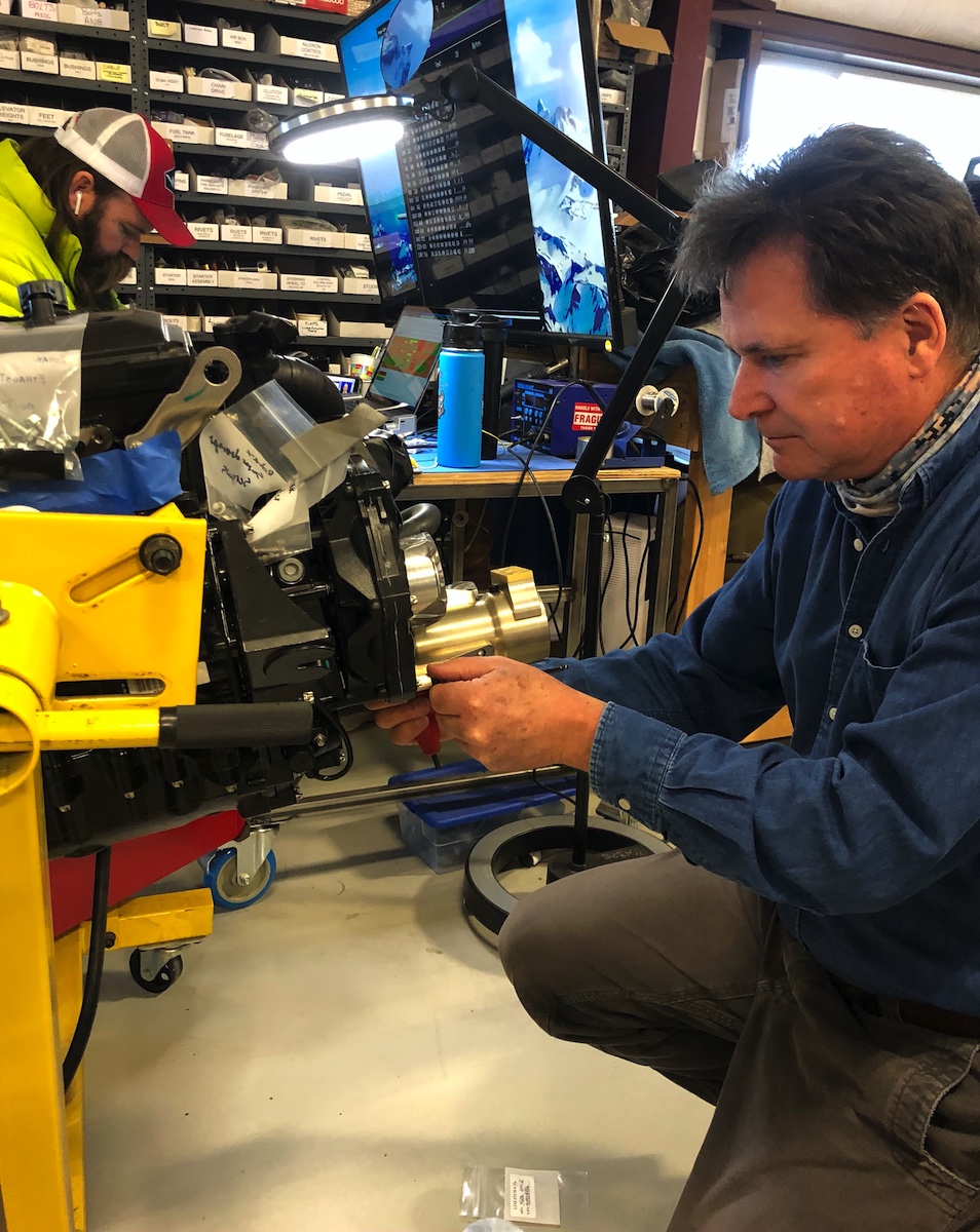 Image 1-23-21 at 12.51 PM Sam Bousfield is shown fitting a power shaft housing to the new engine. This is one of a dozen new assemblies for the new engine installation, and it houses the output shaft from the engine.