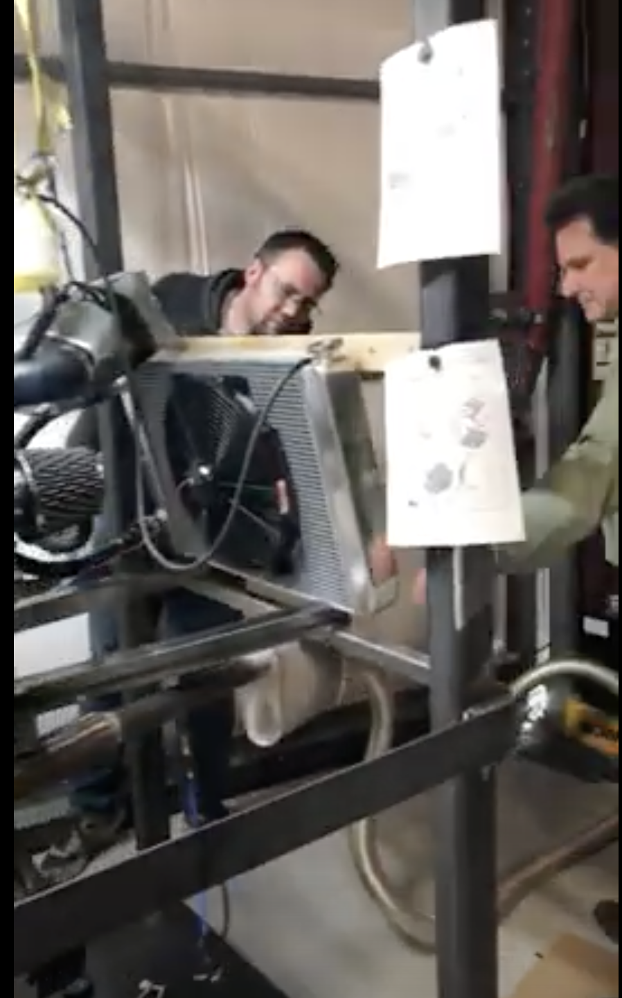 screenshot of video showing two men working on an engine