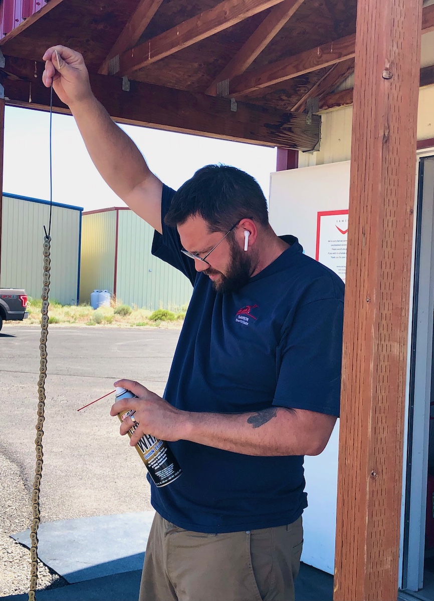 Sean spraying chain 7.06.21 person spraying an engine chain with lubricant