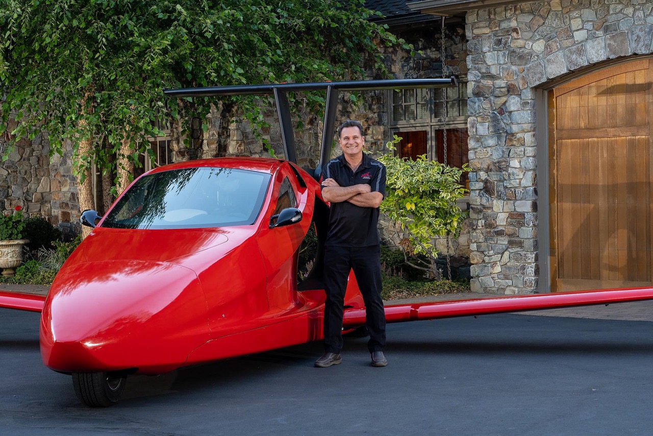 sam bousfield standing next to a switchblade flying car